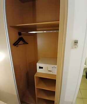 Un armario de madera con una percha y un dispositivo electrónico blanco sobre una estantería.