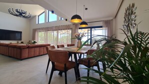 Een moderne woonkamer met een bank, eettafel, stoelen en een televisie.
