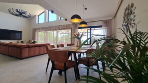 Ein modernes Wohnzimmer mit einer Couch, einem Esstisch, Stühlen und einem Fernseher.