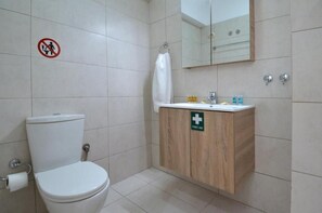 Une salle de bain avec des toilettes, un lavabo et un miroir.
