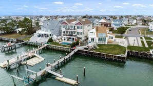 Una propiedad frente al agua con muelle, piscina y una casa grande de varios pisos y balcones.