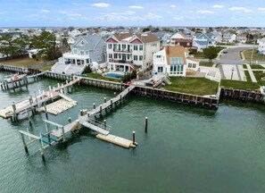 A waterfront property with a dock, a swimming pool, and a large house with multiple stories and balconies. - Bay front Sunsets in Brigantine - Boat Dock & Deck (Brigantine)