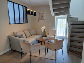 A living room with a sofa, two chairs, a coffee table, a vase with flowers, a painting, and a staircase. - Ti ar Mor Bihan (Riantec)