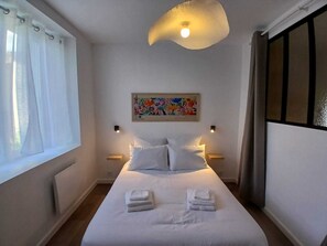 A hotel room with a bed, white curtains, a ceiling light, a wall-mounted painting, and bedside lamps. - Ti ar Mor Bihan (Riantec)