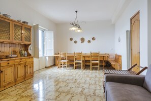 A dining area with a wooden table and chairs, a cabinet with decorative items, and a hanging light fixture.
