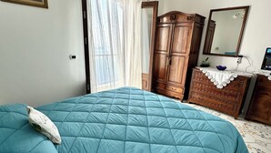 A bedroom with a bed, an air conditioning unit, a wooden wardrobe, a mirror, and a chandelier. - Casa degli Dei, Nocelle-Positano (Nocelle)