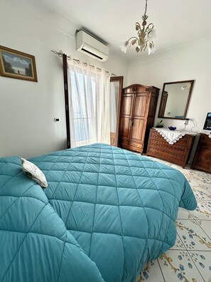Ein Schlafzimmer mit einem Bett, einer Klimaanlage, einem Holzschrank, einem Spiegel und einer Chandelüster.