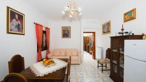 A dining area with a table, chairs, a sofa, a chandelier, and a refrigerator. - Casa degli Dei, Nocelle-Positano (Nocelle)
