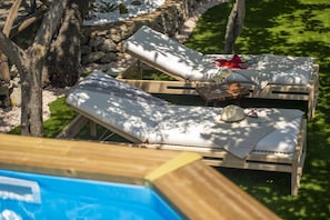 Ein Poolbereich mit Liegestühlen und einem Tisch mit einem Getränk.
