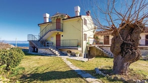 Ein zweistöckiges Haus mit Balkon, einer Treppe und Blick auf das Meer.