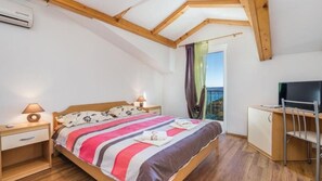 Ein Schlafzimmer mit Bett, Nachttischlampen, einem Fernseher und Blick ins Freie.
