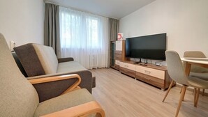 Un salon moderne comprenant un canapé, un téléviseur, un meuble en bois et un coin repas.