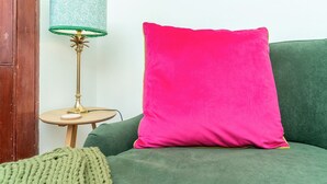 A green sofa with a bright pink pillow and a lamp with a green lampshade on a small wooden table. - Cosy 2 Bed in Central Edinburgh - Pass the Keys (Edinburgh)