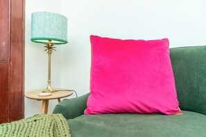 A green sofa with a bright pink pillow and a lamp with a green lampshade on a small wooden table. - Cosy 2 Bed in Central Edinburgh - Pass the Keys (Edinburgh)