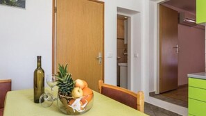 A dining area with a table set for two, a bottle of wine, and a bowl of fruit. - Apartman Butterfly 2 - Opatija by Villas Guide (Brsec)