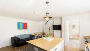 Una cocina moderna con encimera de madera, estufa integrada y comedor con sillas y mesa.