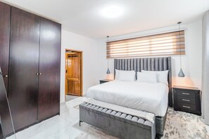 A bedroom with a bed, bedside tables, a wardrobe, and a window with blinds. - Boutique Hotel-Style Room In Ferndale-F6 (Randburg)