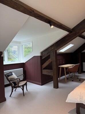 A room with a sloped ceiling, wooden beams, a desk, a chair, and a radiator. - Sleeps 16 | Georgian Manor, Yorkshire Dales, Dent | Dog-friendly, 5 acres (Dent)
