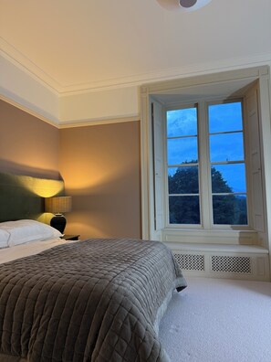 A hotel room with a bed, a nightstand, a lamp, and a window with a view of trees. - Sleeps 16 | Georgian Manor, Yorkshire Dales, Dent | Dog-friendly, 5 acres (Dent)
