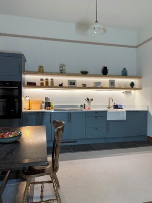 A modern kitchen with blue cabinets, a wooden dining table, and a hanging light fixture. - Sleeps 16 | Georgian Manor, Yorkshire Dales, Dent | Dog-friendly, 5 acres (Dent)
