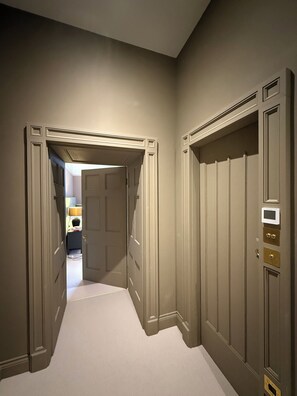 A hallway with a door leading to a room, a thermostat on the wall, and a carpeted floor. - Sleeps 16 | Georgian Manor, Yorkshire Dales, Dent | Dog-friendly, 5 acres (Dent)