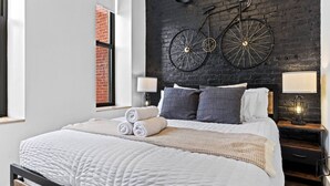 Ein modernes Schlafzimmer mit einem großen Bett, zwei an der Wand befestigten Fahrrädern und einer Ziegelwand.
