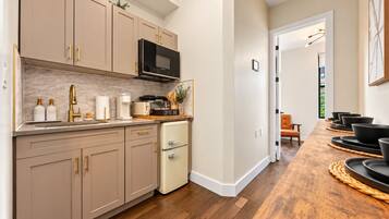 A kitchen with beige cabinets, a microwave, a coffee maker, and a coffee bar sign.
