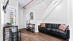 A modern loft with a dining area, a black leather sofa, and a staircase.