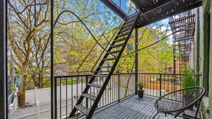 A balcony with a metal staircase, a chair, and a potted plant.
