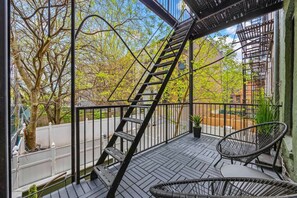 Een balkon met een metalen trap, een stoel en een bloempot.