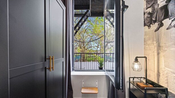 A modern interior with a large window, a small step leading to a balcony, and a wall-mounted lamp.