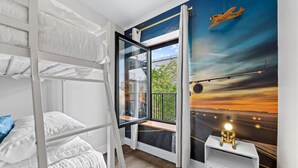 Ein Schlafzimmer mit Etagenbett, großem Fenster, Nachttisch und einem Wandgemälde eines Flugzeugs.