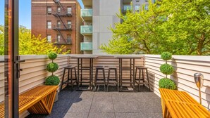 A rooftop terrace with a wooden bench, a small table, and a chair.