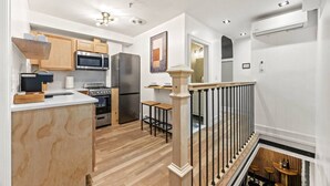 A modern kitchen with wooden cabinets, stainless steel appliances, and a wooden dining area.