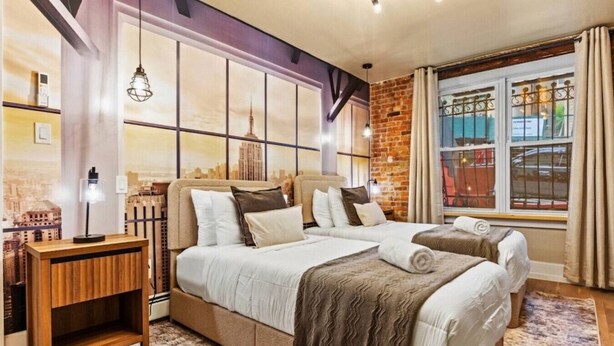 A hotel room with a large bed, a desk, and a window with curtains.