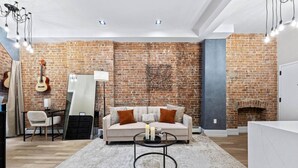 Un salon avec un mur en briques, un canapé, une table basse et une guitare.