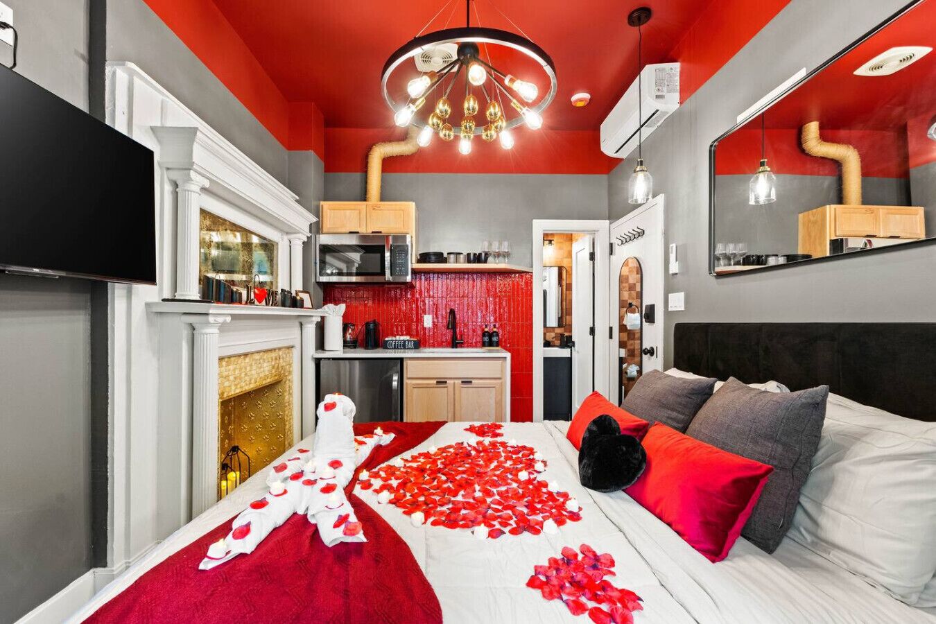 Una habitación de hotel con cama, chimenea, zona de cocina y espejo.