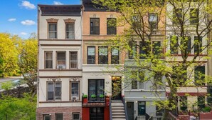 A row of multi-story buildings with a fire escape, a visible address sign, and a tree in the foreground. - Romantic Manhattan Micro-Suite + Private Balcony (New York)