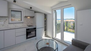 A modern kitchen with built-in appliances, a glass dining table, and a balcony with a view. - #3 Holiday Apartment MTG - Orebić (Orebić)