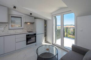 Una cocina moderna con electrodomésticos integrados, una mesa de comedor de vidrio y un balcón con vistas.