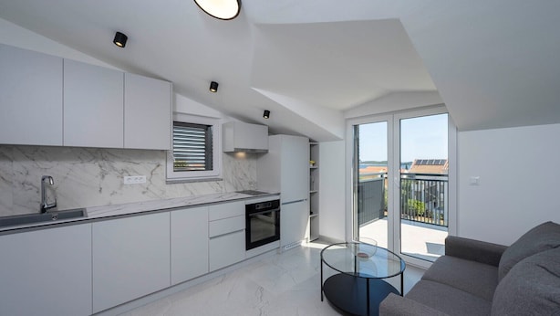 A modern kitchen with white cabinets, a marble countertop, and a glass dining table. - #3 Holiday Apartment MTG - Orebić (Orebić)