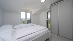 A bedroom with two beds, a window, and a wardrobe.
