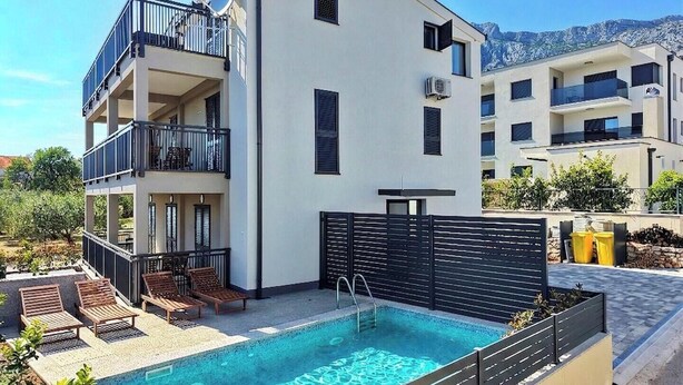 A modern building with a pool, balconies, and a mountain view.