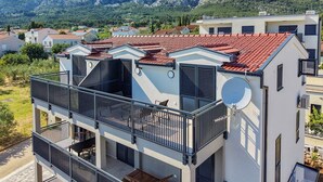 A modern two-story building with a balcony, satellite dish, and a view of a mountainous landscape.