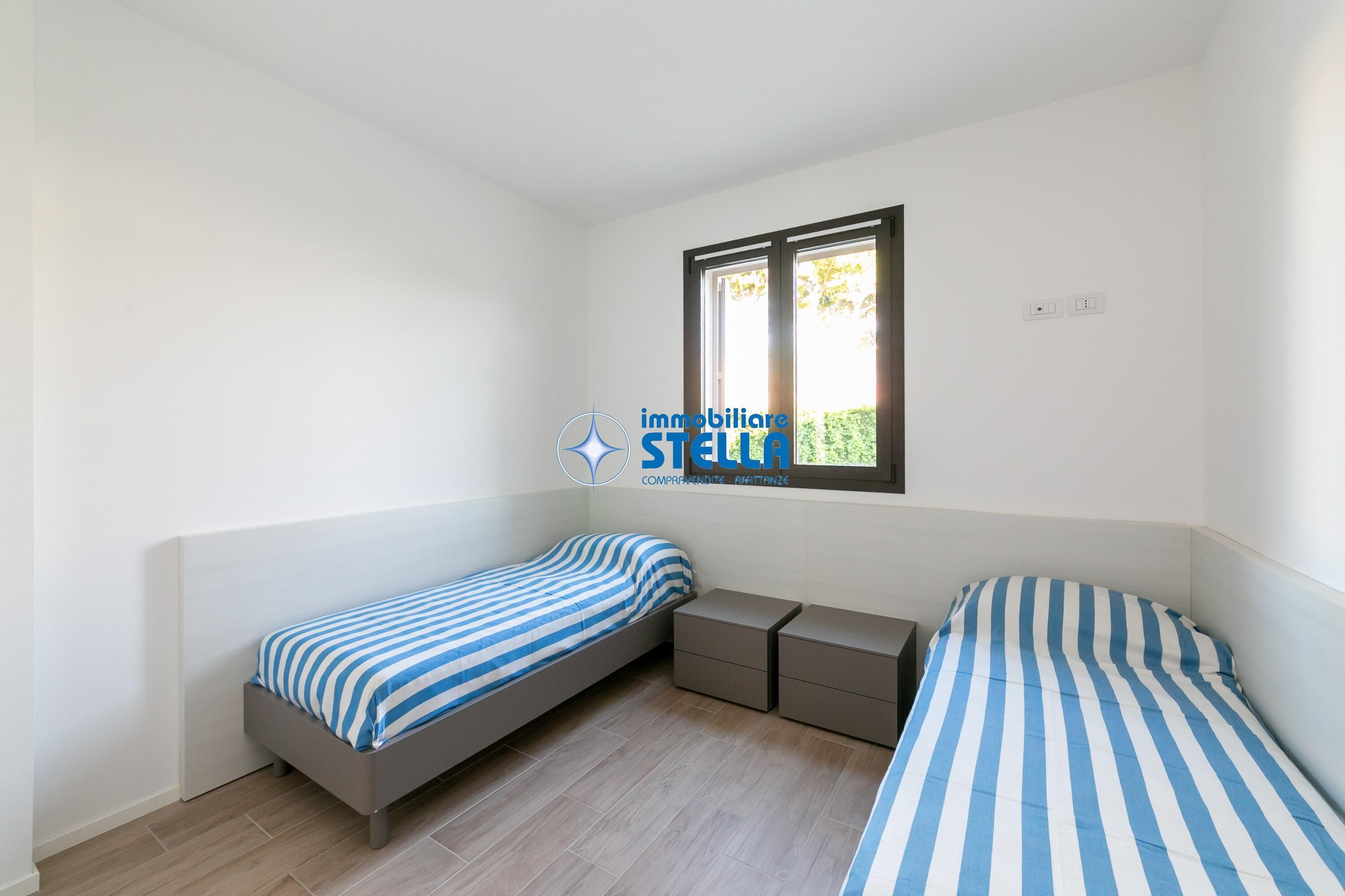 Una camera da letto con due letti singoli, una finestra e un comodino.