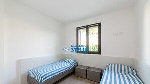 Ein Schlafzimmer mit zwei Einzelbetten, einem Fenster und einem kleinen Nachttisch.