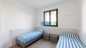 Una camera da letto con due letti singoli, una finestra e un comodino.