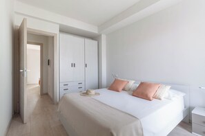 Una camera da letto con un letto, comodini, un armadio e una porta che dà su un'altra stanza.