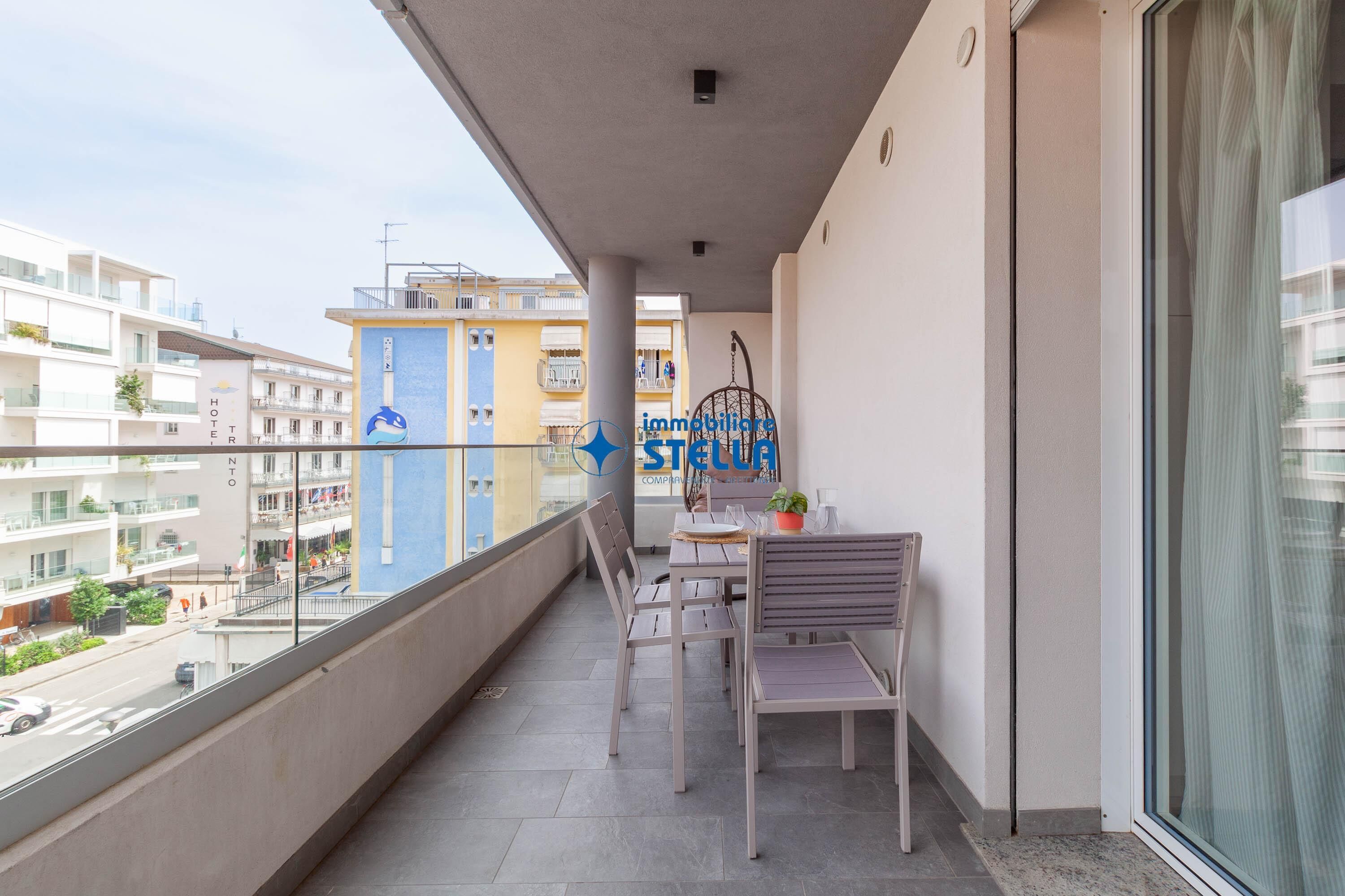 A balcony with a table and chairs, a hanging chair, and a view of buildings.