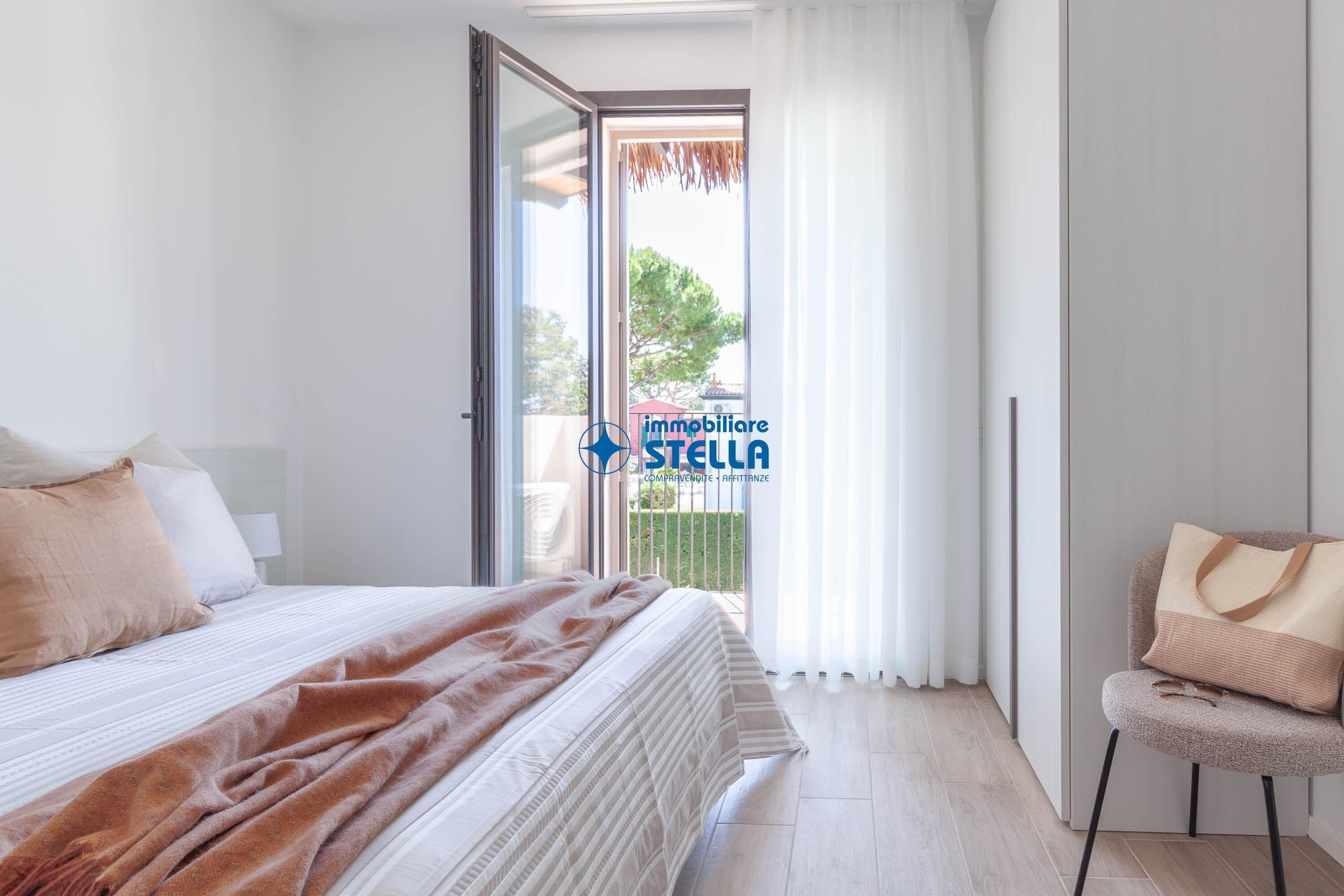 Un dormitorio con cama, una silla, ventana con cortinas y vistas al exterior.